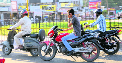 A youth uses a mobile phone while riding a motorcycle in Jammu on Monday. 