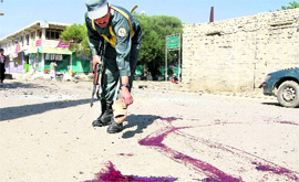 An Afghan policeman inspects the scene of a suicide bomb attack in Khost province on Monday.
