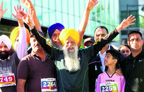 Fauja Singh (101) raises his arms to supporters before running in the 5-km race during the Surrey International World Music Marathon in Canada. Fauja Singh is considered the oldest marathon runner in the world.