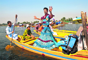 A Kashmiri folk artist performs dance on a shikara during the Shikara Festival in Srinagar on Tuesday. 