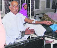 Ambala Central Jail inmate Jai Pal (66) sits handcuffed in the Civil Hospital, Ambala City. 