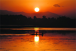 Two youths enjoy a boat ride on the Dal Lake as the sun sets in Srinagar on Wednesday