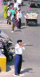 A policeman covers his nose while regulating traffic in Ludhiana on Wednesday. 