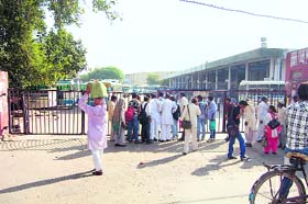 Passengers wait outside the main gate of the Sonepat bus stand on Thursday