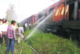 Railway employees try to douse the flames in a diesel engine at Ambala railway station on Thursday