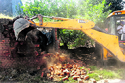 An earth-moving machine demolishes an illegal structure at a park in Haibowal on Friday