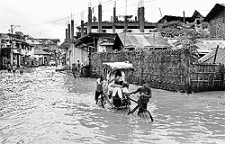 A rickshaw-puller wades through a flooded street of Dhobinala after a heavy downpour in Dimapur, Nagaland, on Friday