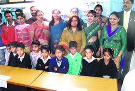 Members of Prerna, an NGO, and the Freemasons Community distribute tables among students of Kolti village school in Mussoorie on Monday