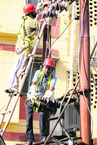 Daily wagers of the Power Development Department work with safety gears in Jammu on Monday.