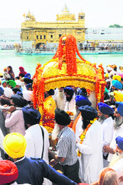 Devotees carrying a palanquin during a procession on the eve of the birth anniversary of Guru Ramdass in Amritsar on Monday. 
