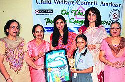 Ritu Aggarwal, wife of the Deputy Commissioner, presents a prize to a winner of an on-the-spot painting competition at Red Cross Bhawan in Amritsar on Wednesday