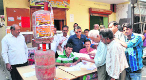 BJP supporters put LPG cylinders on a table to remind voters of price rise outside a polling station in Dehradun on Wednesday. 