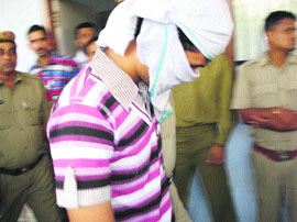 A rape accused with covered face comes out of a court in Kaithal on Wednesday. 