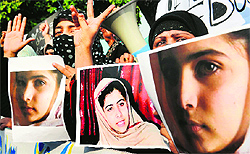 Activists carry photographs of Malala Yousafzai, who was attacked by the Taliban, during a protest in Lahore