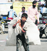 A minor boy carries trash bags at the City Chowk in Jammu on Saturday.