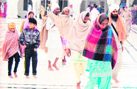 Devotees wrap themselves in shawls and other warm clothes following a sudden dip in temperature at the Golden Temple complex in Amritsar.