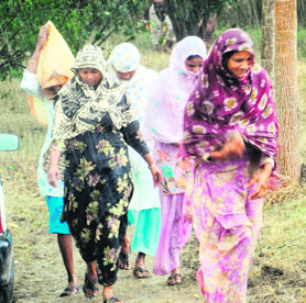 Women cover themselves with dupattas as sudden showers lash the city on Monday.