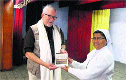 Robert Hutchinson presents his latest book to Sister Lucy in Mussoorie on Monday.