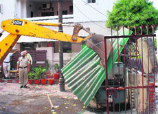 An MC ditch machine demolishes an illegal structure in the Shastri Nagar area of Ludhiana on Monday.