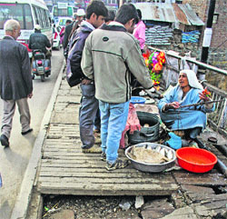 A woman sells fish on the damaged portion of Amira Kadal bridge in Srinagar.