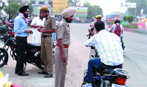 Cops stop commuters to check their documents near Bibiwala Chowk.