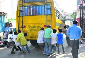People try to stop the bus ferrying schoolchildren after its brakes failed near Raghunath temple in Jammu on Wednesday