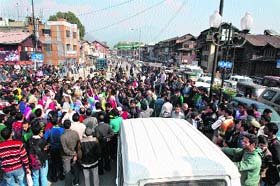 People raise anti-government slogans during a protest at Budshah bridge in Srinagar on Wednesday