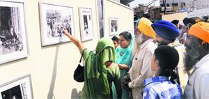 Visitors look at a photo exhibition on the 1984 anti-Sikh riots at Dharam Singh Market Chowk in Amritsar on Sunday. 