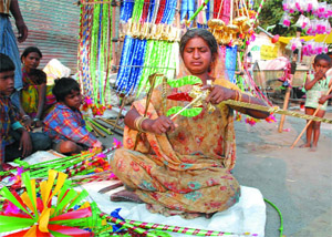 A woman is busy making a toy trident for sale on the eve of Dussehra in Bathinda on Tuesday. 