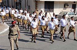 A policemen walks ahead as activists of the Rashtriya Swayamsewak Sangh (RSS) take out a march in the city on Wednesday to mark their foundation day