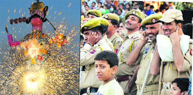 Police personnel cover their ears as (left) the effigy of Ravan sets on fire in Jammu on Wednesday.