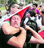 A Palestinian activist is arrested by Israeli soldiers as dozens of Palestinians block the entrance to branch of the Rami Levy supermarket opened in Shaar Binyamin close to the city of Ramallah