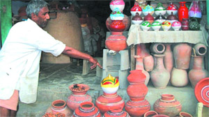 A potter points at an earthen ware to prospective buyers on Amrik Singh road in the city on Thursday.