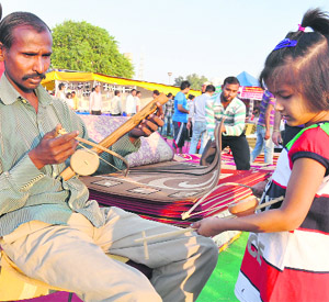 This child tries her hand at a sarangi during a handicraft mela at Leisure Valley Park in Gurgaon.