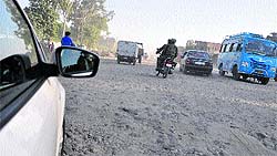 Vehicles move on a dilapidated Kunjwani-Satwari National Highway in Jammu on Thursday