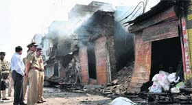 Police officials inspect torched shops in Faizabad on Thursday.
