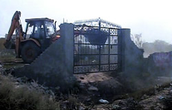 A JCB machine demolishes the main gate of an unauthorised construction in Kharkhoda. 
