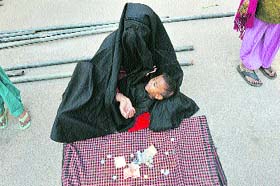 A woman holds her son as she seeks alms near Eid Gah ground in Jammu on Saturday.