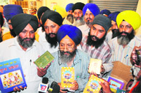 Activists of the Sri Guru Granth Sahib Satkar Committee and SGPC employees show seized Sikh religious books in Amritsar