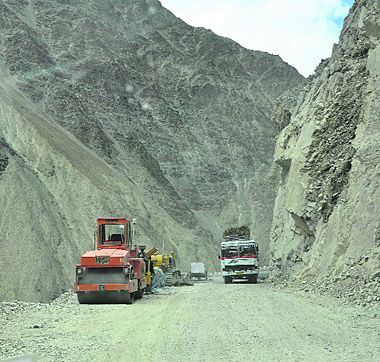 A bus moves on a dilapidated road in the Ladakh region.