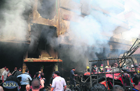 A crowd gathers in front of a building damaged by a car bomb in Jaramana district, near Damascus, on Monday.