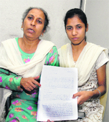 Bimla Devi, accompanied by her daughter, shows a property-related document in Jalandhar on Tuesday. 