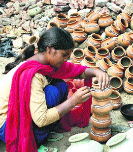 Ahead of Karva Chauth and Divali, a girl paints earthen pots in Rohtak on Wednesday.