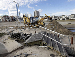 A worker uses a backhoe to clear sand and debris that was carried onshore by a surge from superstorm Sandy in Atlantic City on Wednesday.