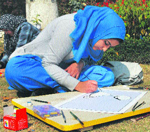 A student participates in a painting competition during the Intra-University Youth Festival in Srinagar.