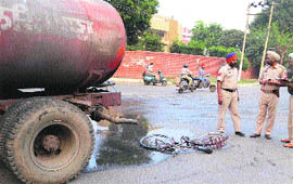 Police personnel stand near the cycle that was hit by an MC water tanker in Ludhiana