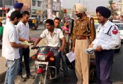 NSS volunteers of the PTUGZS campus distribute pamphlets to motorbike riders to make them aware of traffic rules in the city on Friday.