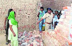 A policeman surveys a razed wall in a house as terrified owner, Kaushlaya Devi, looks on at Gurunanakpura in Fatehabad on Sunday
