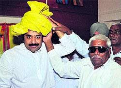 HJC supremo Kuldeep Bishnoi dons a yellow turban matching the colour of his partys flag offered by a supporter at Fatehabad