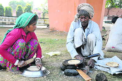 Migrants from Rajasthan prepare food in the open at Dogra Chowk in Jammu on Sunday. 